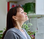 Woman with eyes closed and head tilted upwards inhaling clean air after duct service in Ocean County