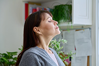 Woman with eyes closed and head tilted upwards inhaling clean air after duct service in Ocean County
