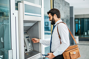 Person using an ATM serviced and sold by NCR dealers in NJ