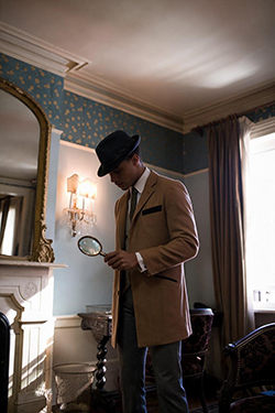 Man in trench coat holding magnifying glass standing in front of a fireplace; Chimney service Brick Detective